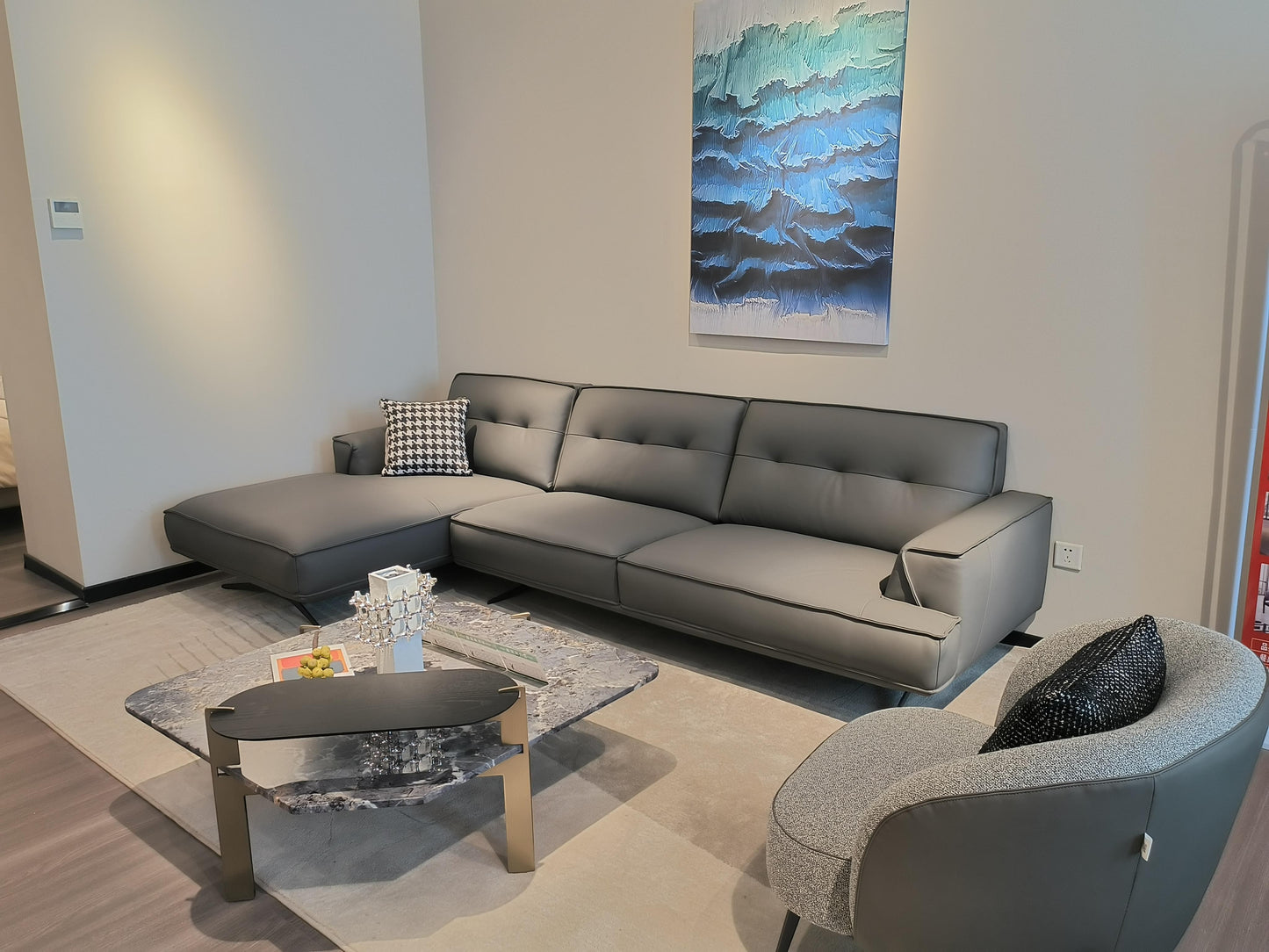 Ambrosia Concepts grey leather L-shaped sectional sofa with chaise lounge and tufted cushions.