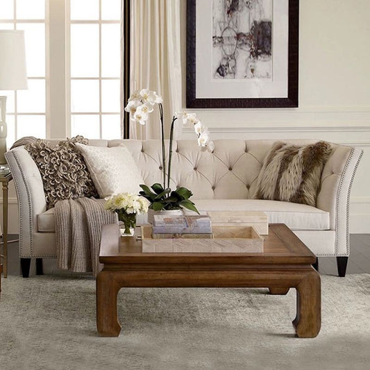 Ambrosia Concepts Old Trafford 3 Seater sofa in neutral fabric with tufted back, nailhead trim, and curved arms. Styled with plush cushions and a throw.