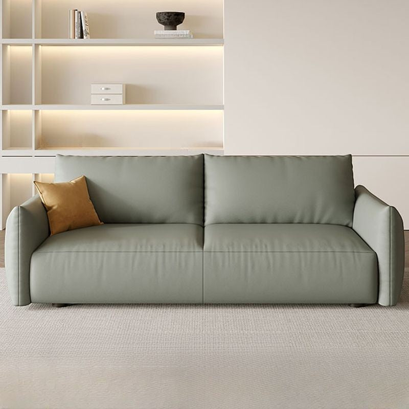 Ambrosia Concepts Kreta 3-seater sofa in sage green faux leather with clean lines and plush cushioning, featuring a single ochre throw pillow.